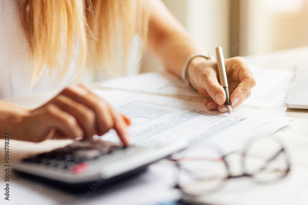 Business woman writing make note in tax form, next lying calculator. Business financial and accounting concept. Business woman writing make note in tax form, next lying calculator. Business financial and accounting concept.