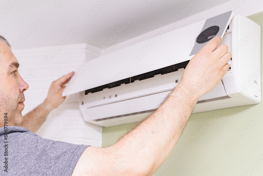 Fototapeta premium a man removes the cover of the air conditioner for the cleaning indoors