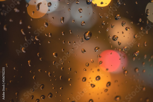 Raindrops on blue glass background. Street bokeh out of focus. abstract background