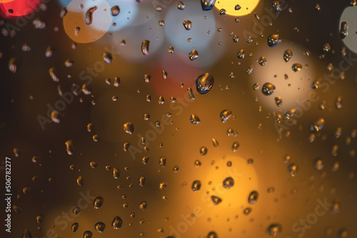 Raindrops on blue glass background. Street bokeh out of focus. abstract background