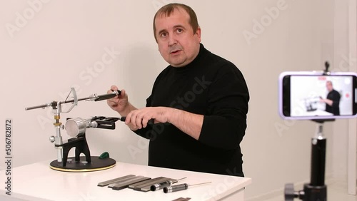 blogger conducts an online master class on sharpening knives on a hand machine.