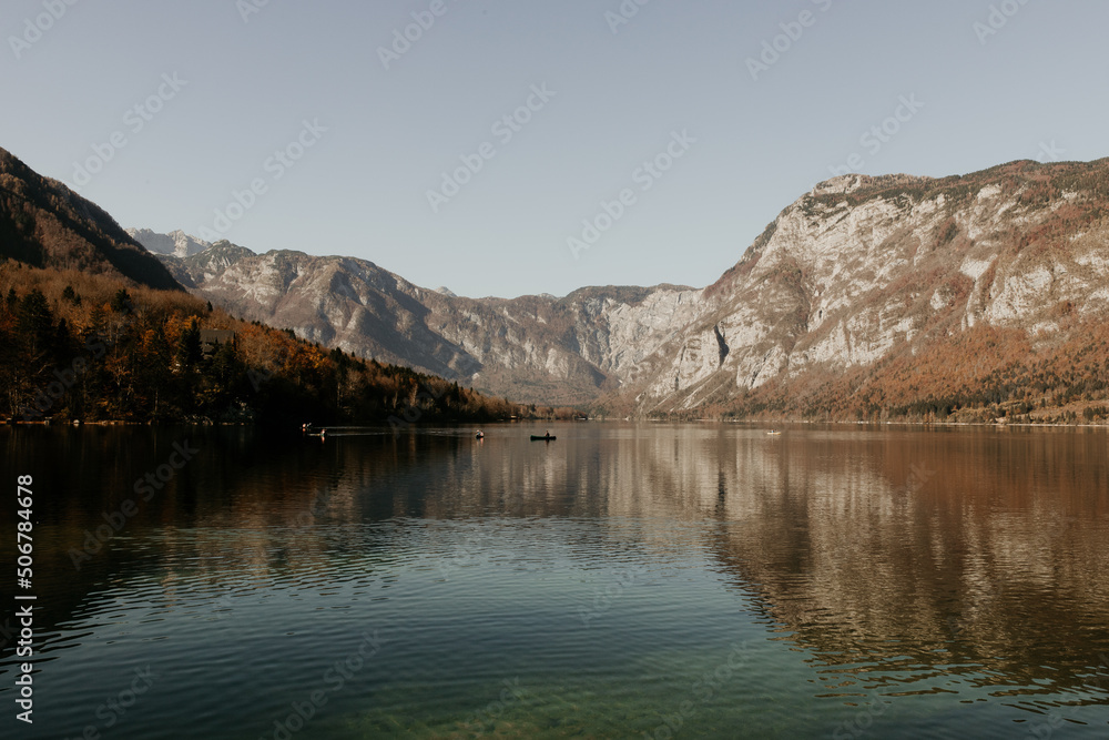 A stunning landscape at lake Bohinj in Slovenia. Beautiful mountain and cristal clear water. Reflection on water. Daylight and soft lights. Boat on the image. Autumn in the Alps. Place to visit.	