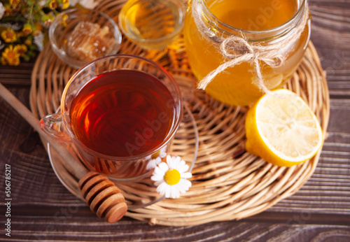 Cup of herbal tea with lemon and honey in jar on the tray.