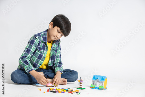 Happy indian child boy playing colorful blocks toy, isolated on white studio background. Educational toys for elementary and kindergarten kid.