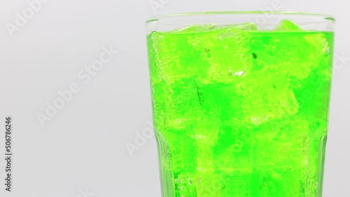 Green sparkling water with Ice in glass. Green sparkling water drink over white background.