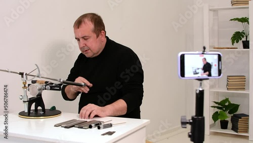 blogger conducts an online master class on sharpening knives on a hand machine.