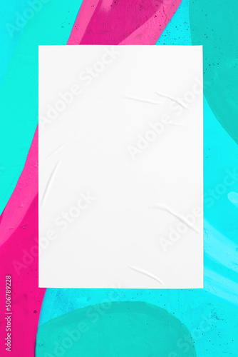 Closeup of colorful messy painted urban wall texture with wrinkled glued poster template. Modern mockup for design presentation. Creative pink mint green blue urban city background. 