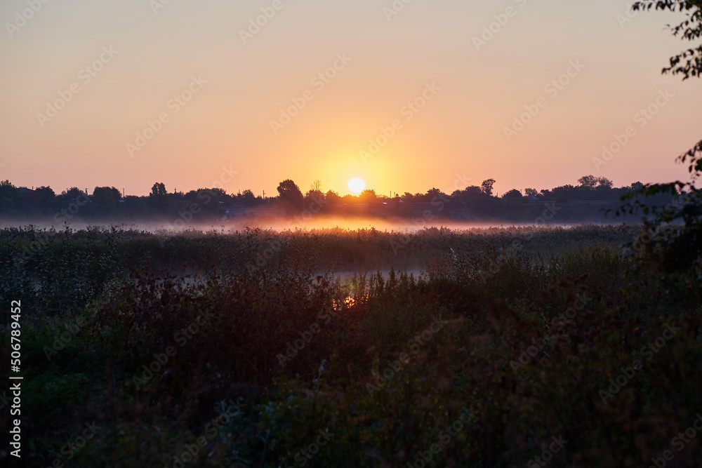 Rural landscape of river and grass on a sunset background