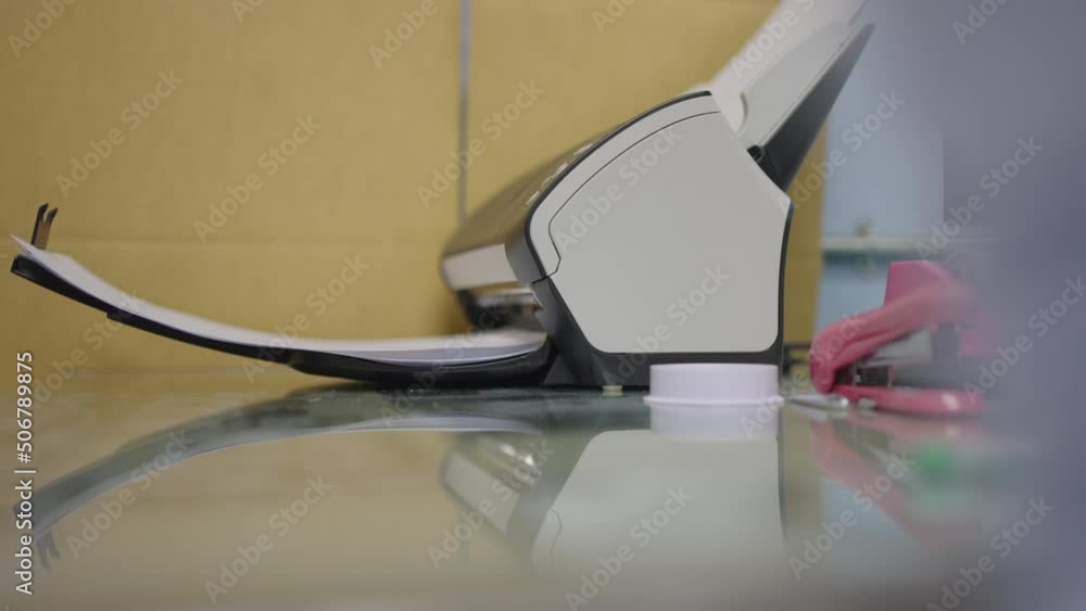 Close-up scanner machine is scanning documents to convert paper to information data digital into computer. Close-up scanner machine is scanning documents to convert paper to information data digital into computer.