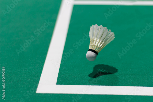 Shuttlecock floating on a green badminton court. Background, taken in low light.