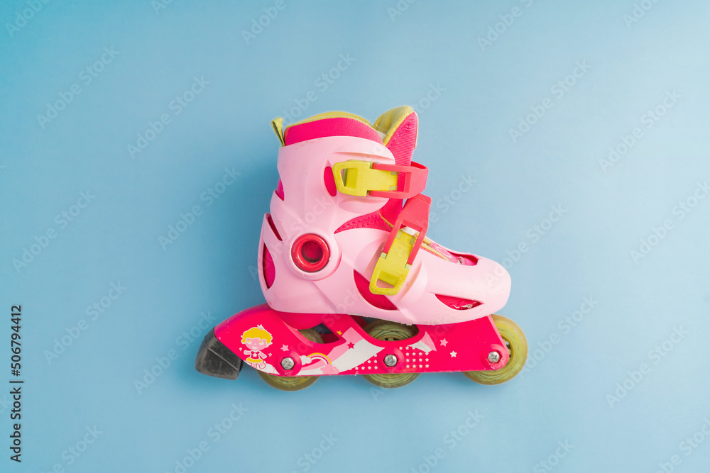 Top view of pink roller skates on blue background, top view minimal kids outdoor activity equipment 