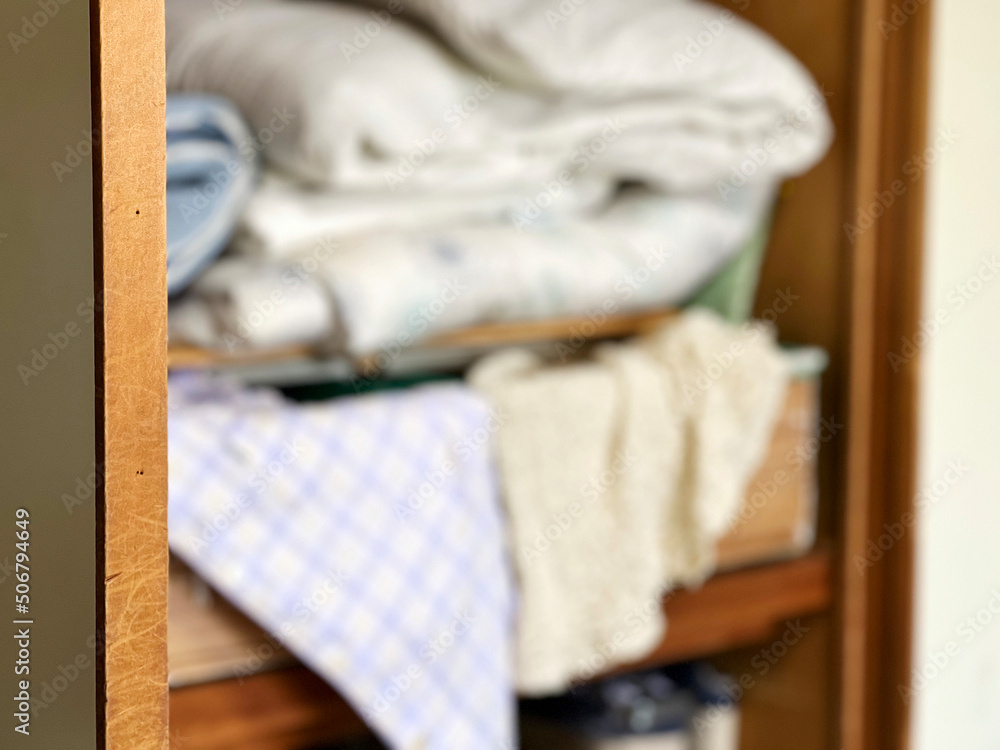 押し入れの中からあふれる毛布や衣類ボカシイメージ
