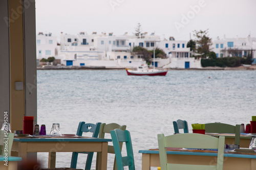 Cafe or restaurant with empty outdoor seating on terrace with sea view and townscape in background
