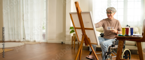 Photographie panoramic of disabled artist senior female drawing sitting on wheel chair at home