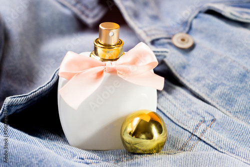 Women's white perfume bottle with pink bow on denim