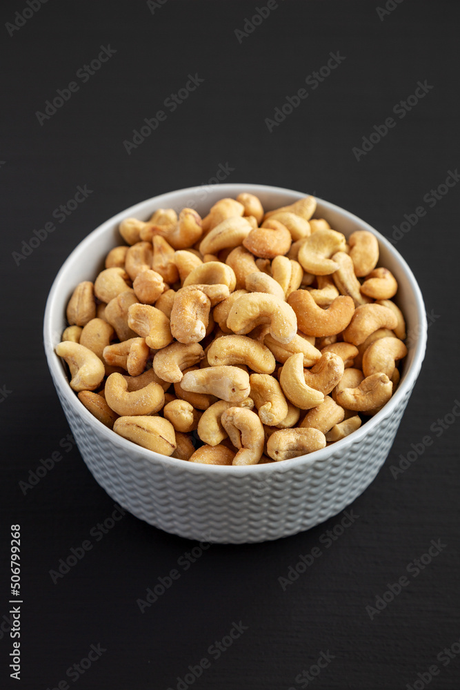 Homemade Roasted and Salted Cashews in a Bowl on a black background, side view.