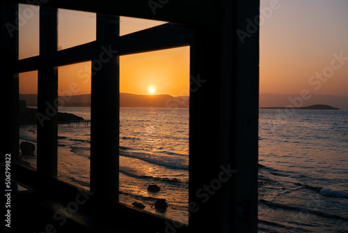 Fototapeta Naklejka Na Ścianę i Meble -  Beautiful sunset scene and sea framed with wooden window frame.