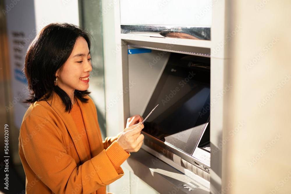 Happy smiling young woman withdrawing money from credit card. Young woman typing pin code on keypad of ATM machine. Happy smiling young woman withdrawing money from credit card. Young woman typing pin code on keypad of ATM machine.