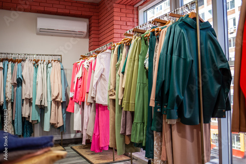 Colorful women's dresses on hangers in a retail shop. Fashion and shopping concept. Women's clothing boutique