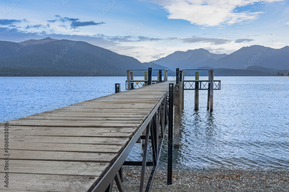 Pier projecting into lake with mountain range background