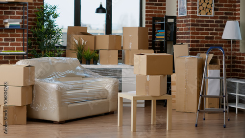 Empty household space with cardboard boxes used for relocation, moving home furniture in carton containers and storage equipment. No people in new apartment flat to move into.