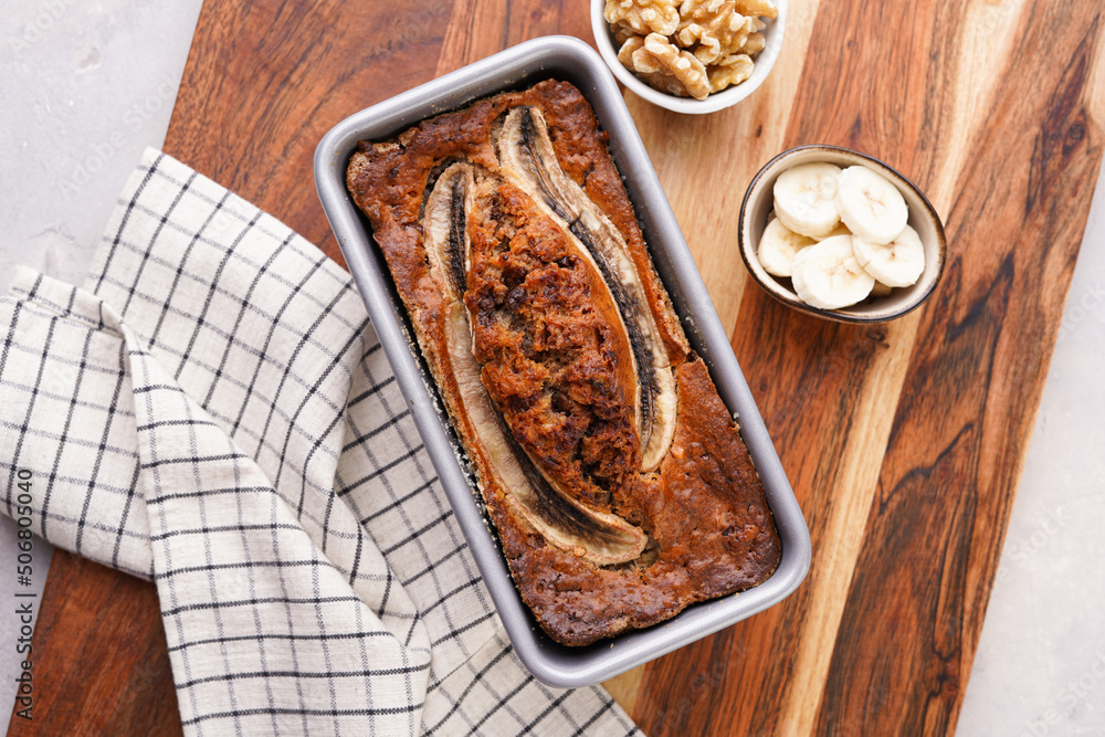 Chocolate banana bread with walnuts in a metallic baking mold on a wooden background, top view Chocolate banana bread with walnuts in a metallic baking mold on a wooden background, top view