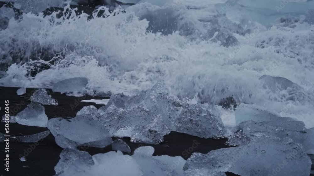 Spectacular waves breaking over icebergs on black sand beach, slow motion Spectacular waves breaking over icebergs on black sand beach, slow motion
