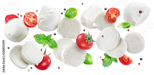 Flying slices of mozzarella cheese with cherry tomatoes, pepper and basil isolated on white background.