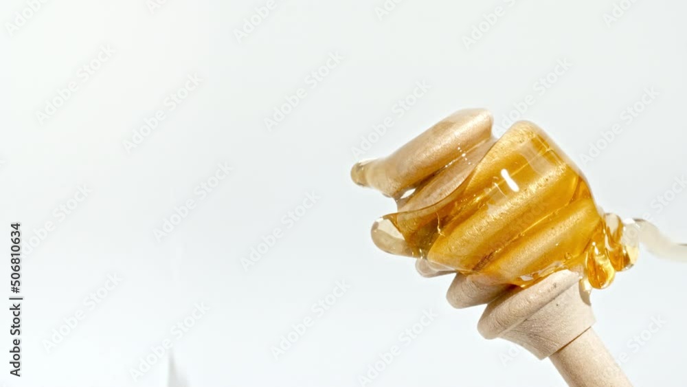 Honey Dripping to a Honey Dipper. Liquid Honey Flows on the Isolated White Background. Healthy Food Concept. Vertical video. Macro Shot. High quality 4k footage Honey Dripping to a Honey Dipper. Liquid Honey Flows on the Isolated White Background. Healthy Food Concept. Vertical video. Macro Shot. High quality 4k footage