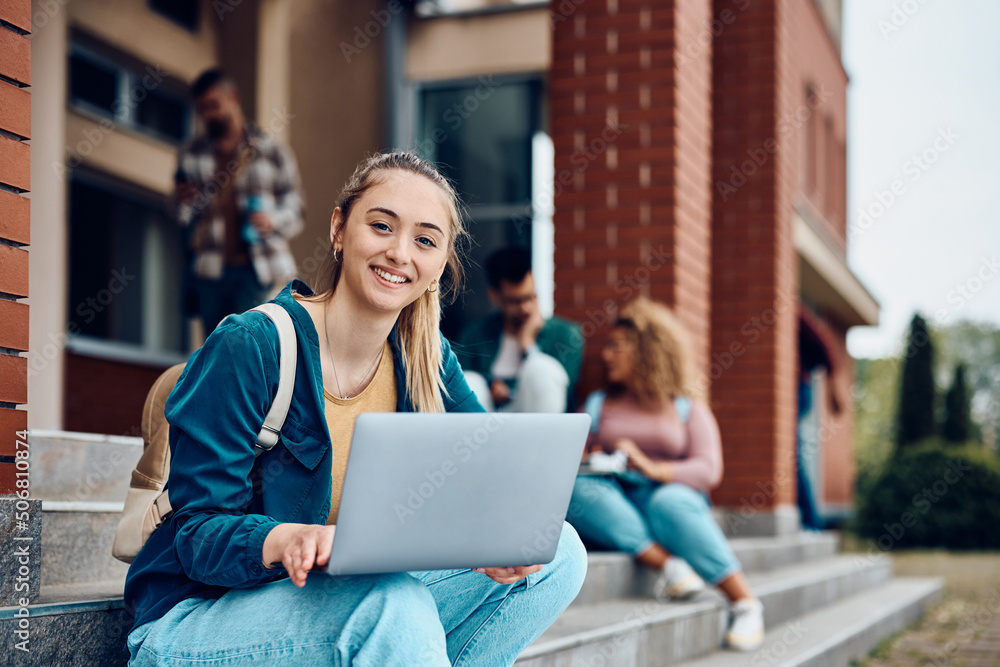 © Drazen - Happy female college student e-learning on laptop at campus and looking at camera. © Drazen - Happy female college student e-learning on laptop at campus and looking at camera.
