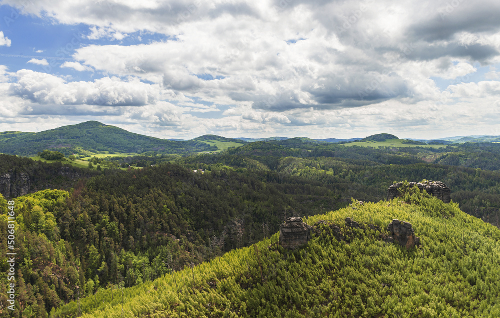 Obraz premium Beautiful view of the landscape of Bohemian Switzerland. The photo shows rocks between trees and clouds in an otherwise blue sky. The photo is taken from the top of Maria Rock.