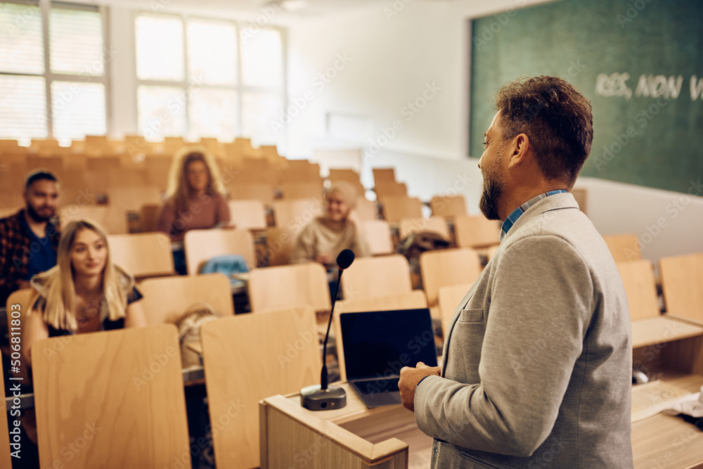 Male professor teaching group of students during class at college classroom.