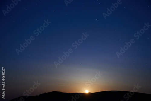 Sunset above mountain and blue dark night sky with stars