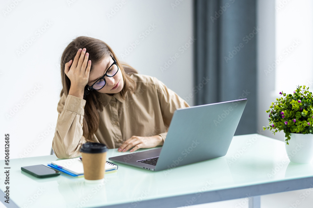 Feeling tired and stressed. Frustrated woman keeping eyes closed and massaging nose while sitting at her working place in office Feeling tired and stressed. Frustrated woman keeping eyes closed and massaging nose while sitting at her working place in office