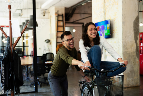 Colleagues in office. Businesswoman and businessman with bicycle. Two friends having fun together.