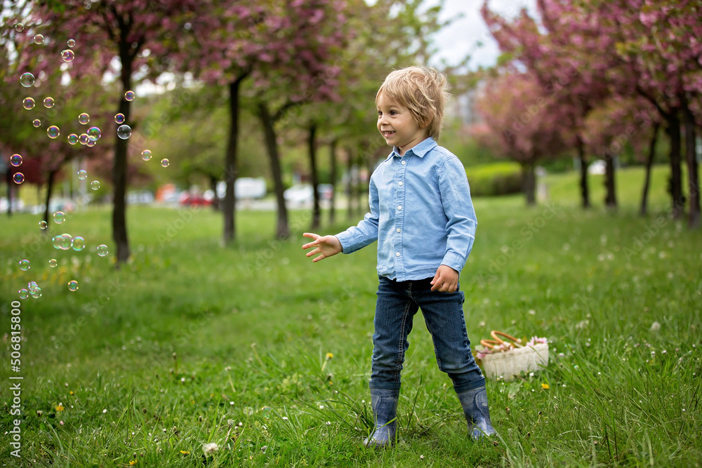 Blond toddler child, cute boy in casual clothing, playing with soap bubbles in the park Blond toddler child, cute boy in casual clothing, playing with soap bubbles in the park