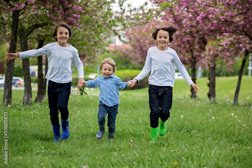 Happy children of different age groups, running together in the park, springtime, having fun