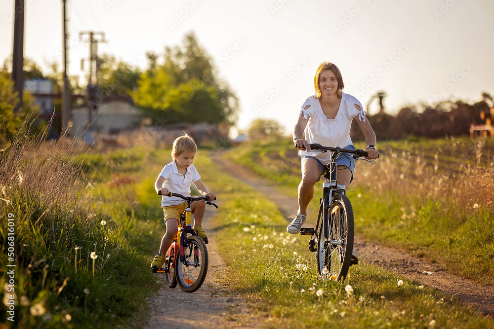 Cute child with pet dog, riding a bike in a rural field on sunset