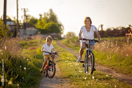 Cute child with pet dog, riding a bike in a rural field on sunset