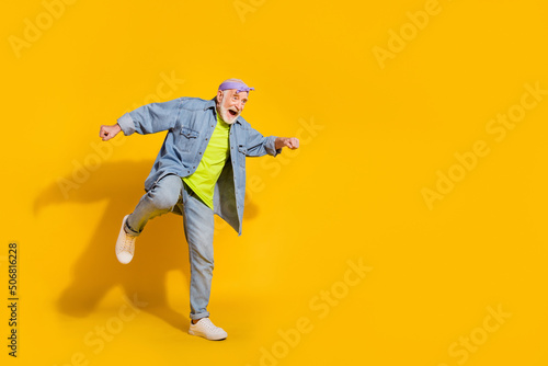Photo of pretty cute man pensioner dressed denim jacket dancing empty space isolated yellow color background