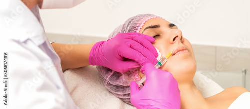 Young caucasian woman getting botox injection with hyaluronic acid in the lips at a beauty clinic