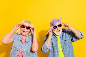 Photo of cool excited husband wife wear jeans shirts hands arms sunglass empty space isolated yellow color background