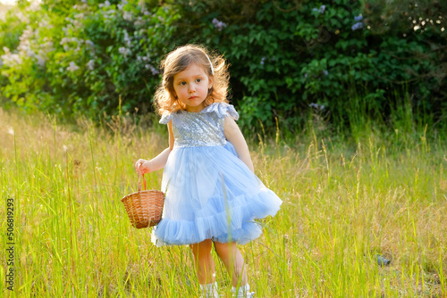 child walks in the park. little girl dressed in a blue dress.