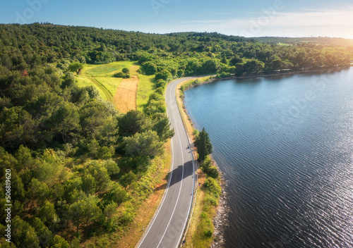 Fototapeta Naklejka Na Ścianę i Meble -  Aerial view of road near blue sea, forest at sunset in summer. Travel in Croatia. Top view of beautiful road, green trees, hills in spring. Colorful landscape with highway and sea coast. Road trip	