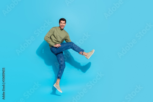 Full body photo of cool millennial brunet guy dance wear shirt jeans footwear isolated on blue background © deagreez