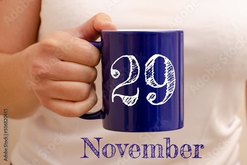 The inscription on the blue cup 29 november. Cup in female hand, business concept