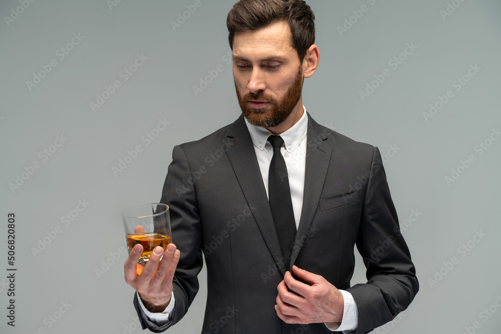 Waist up portrait view of the attractive handsome look at the whiskey from the glass in his hands.Stylish and successful men concept Waist up portrait view of the attractive handsome look at the whiskey from the glass in his hands.Stylish and successful men concept