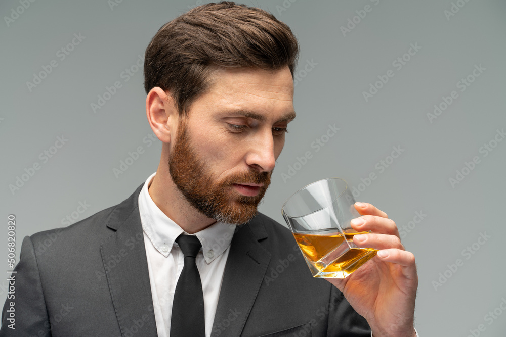 Waist up portrait view of the attractive handsome smells whiskey from the glass in his hands.Stylish and successful men concept Waist up portrait view of the attractive handsome smells whiskey from the glass in his hands.Stylish and successful men concept