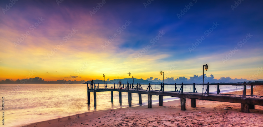 Fototapeta premium Sunrise on Wooden pier on city beach at Nha Trang, Vietnam in a summer day