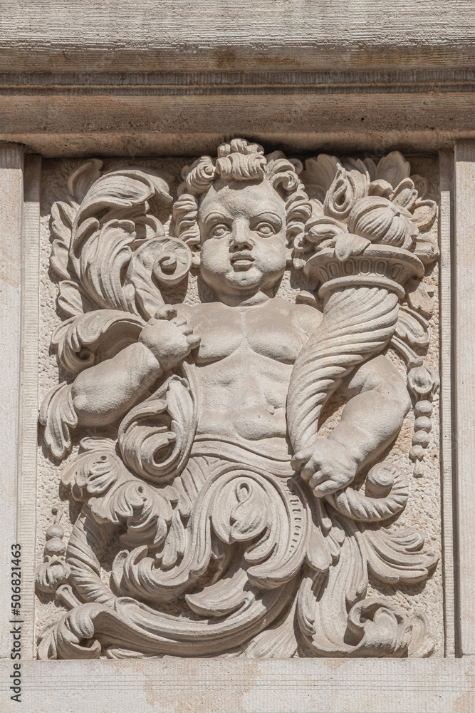 Old relief bar of a small child with Cornucopia, horn of plenty in the historical downtown of Dresden, Germany, details, closeup.
